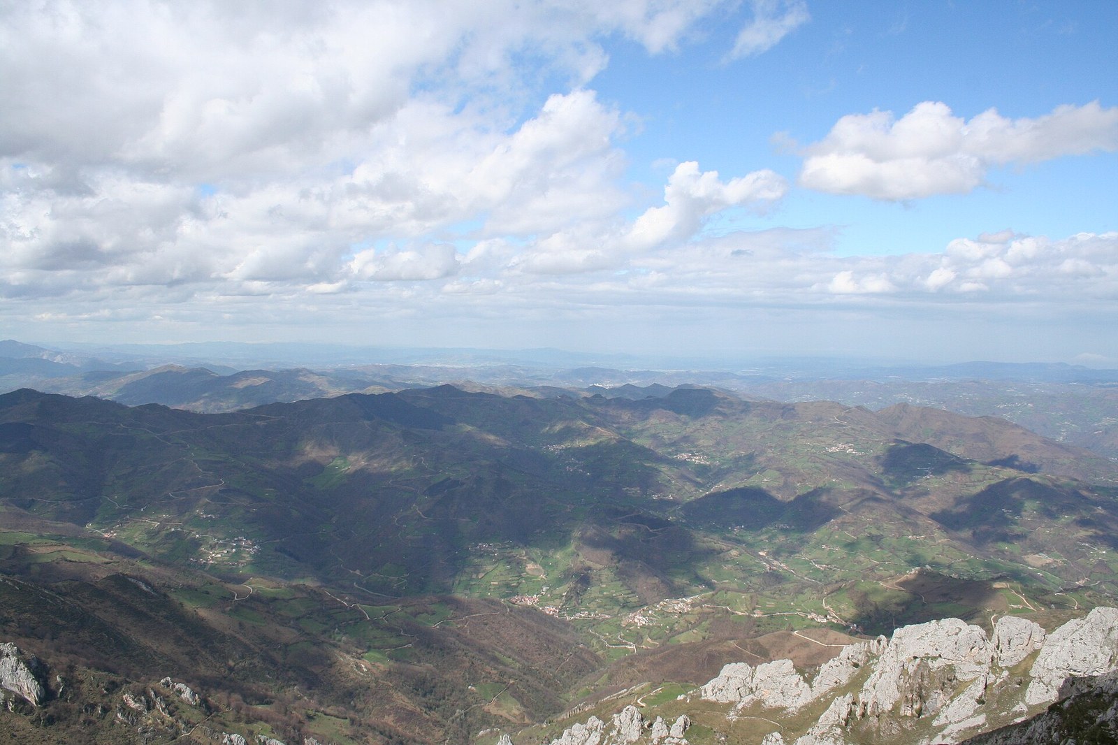 Vista panorámica desde Peña Mea (1564 m, la cumbre más alta del concejo): valles, prados y crestas calizas de Laviana bajo un cielo nublado, sin presencia de personas.